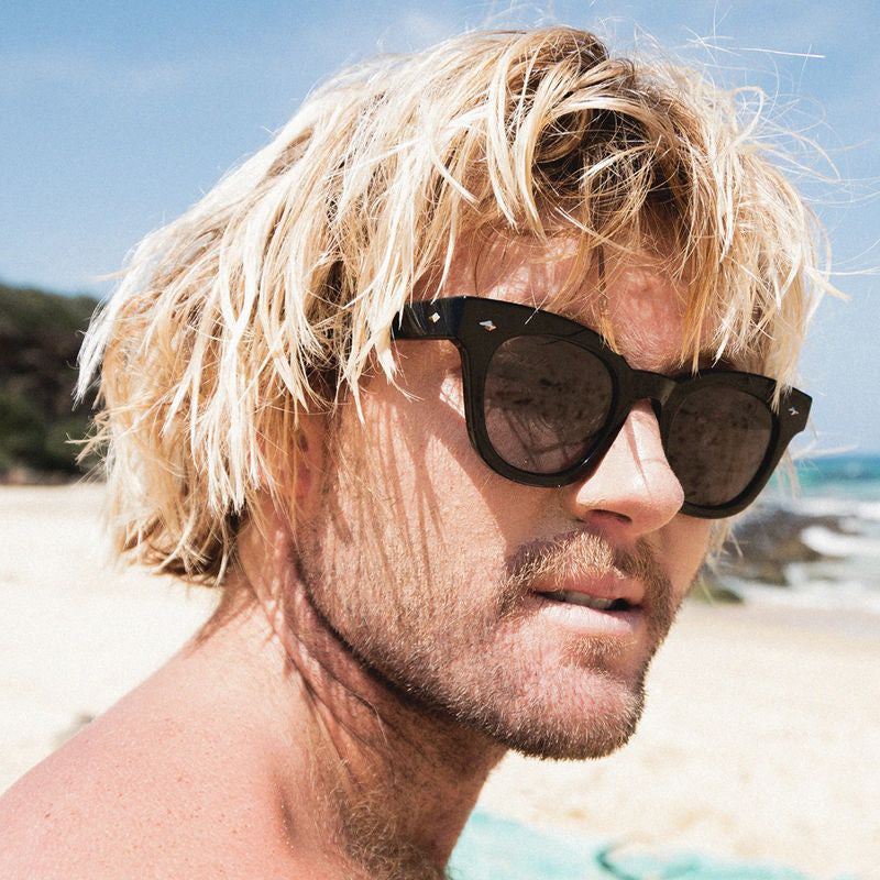Man on the beach wearing cat eye sunglasses