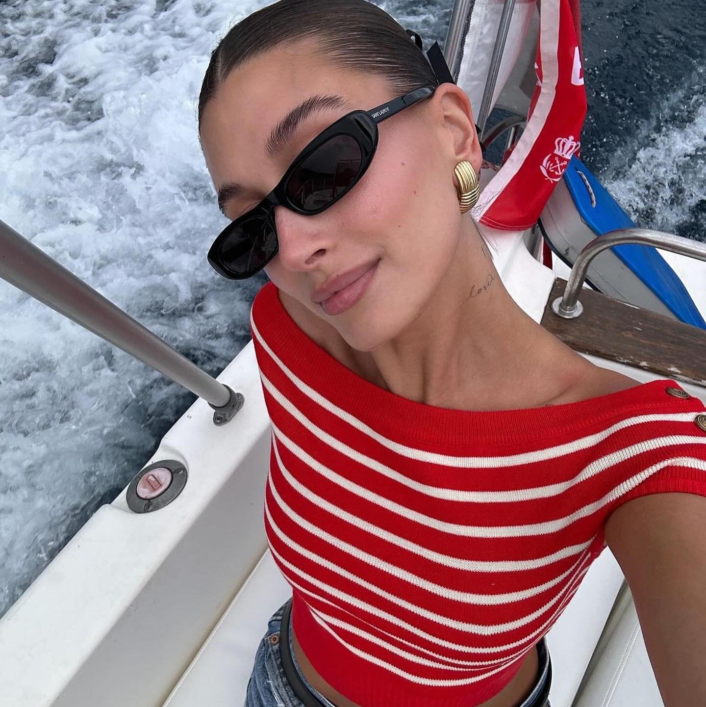 Hailey Bieber wearing a red and white striped shirt and saint Laurent sunglasses