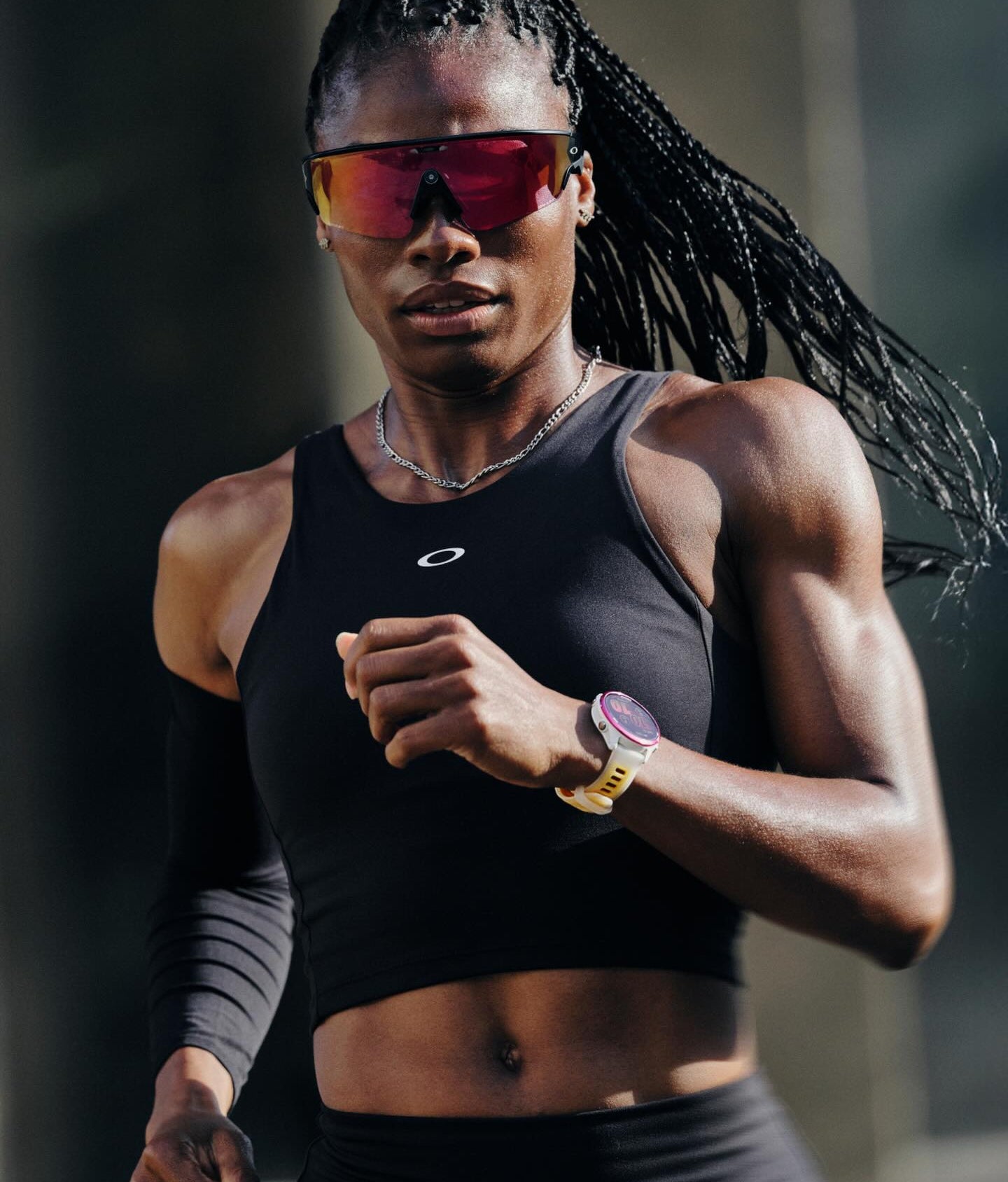 Person running outdoors wearing a black athletic outfit and oakley meta sunglasses
