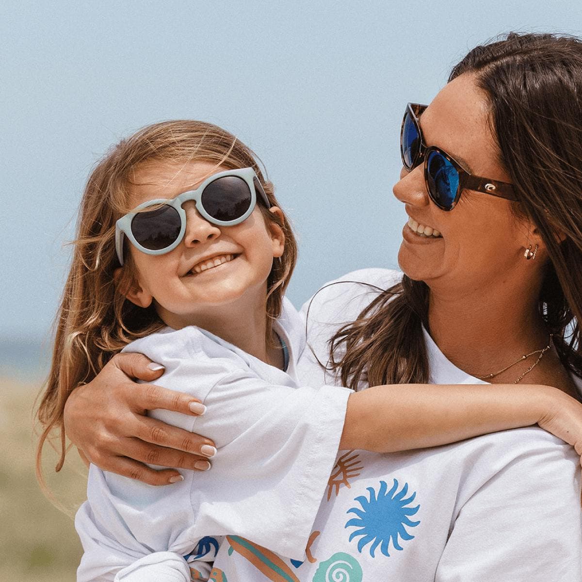 Woman and child wearing sunglasses outdoors with a clear sky background